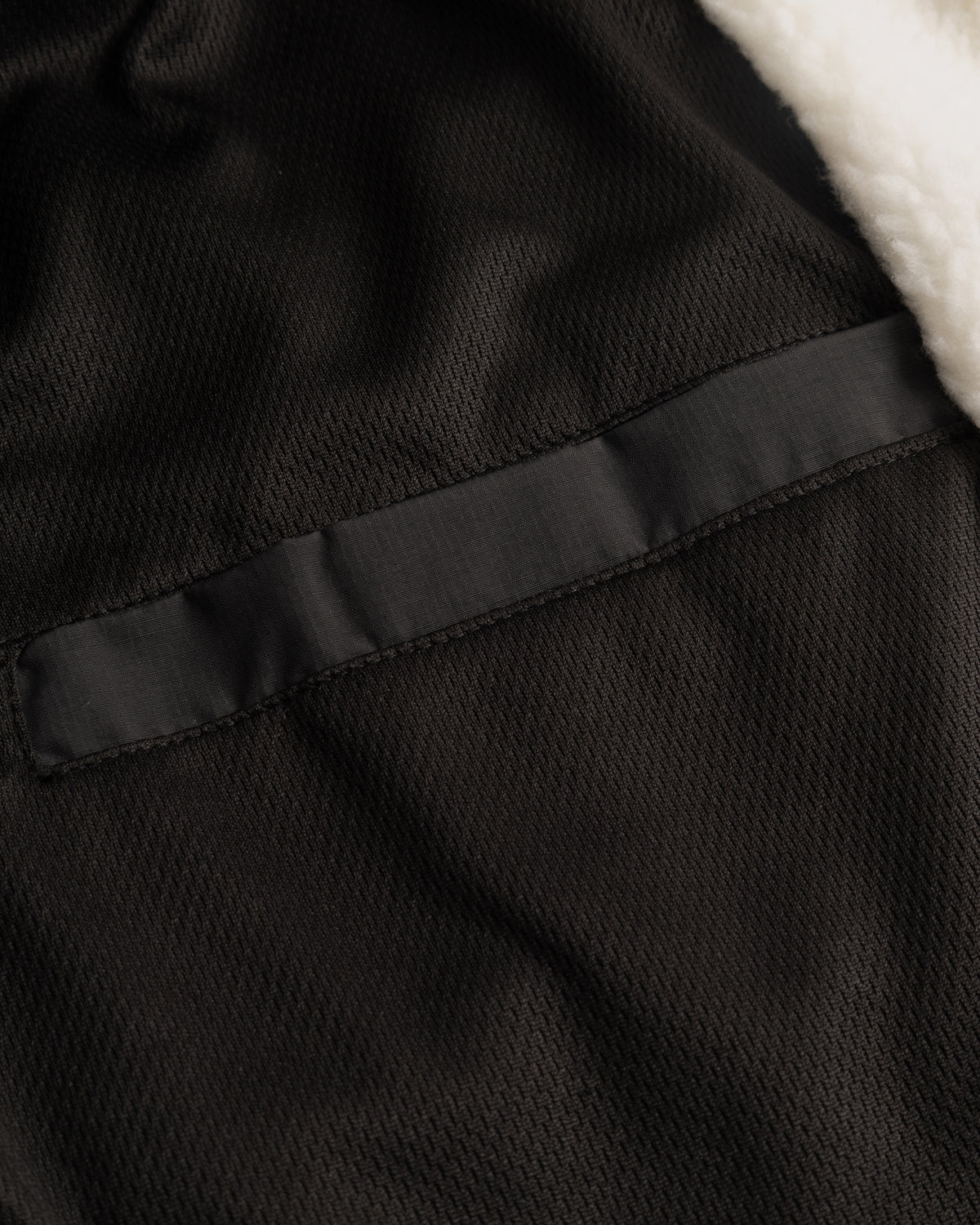 Innenseite der Cropped Teddy Fleecejacke ‚Carey‘ mit schwarzem Textilfutter und weißem Teddyfellrand