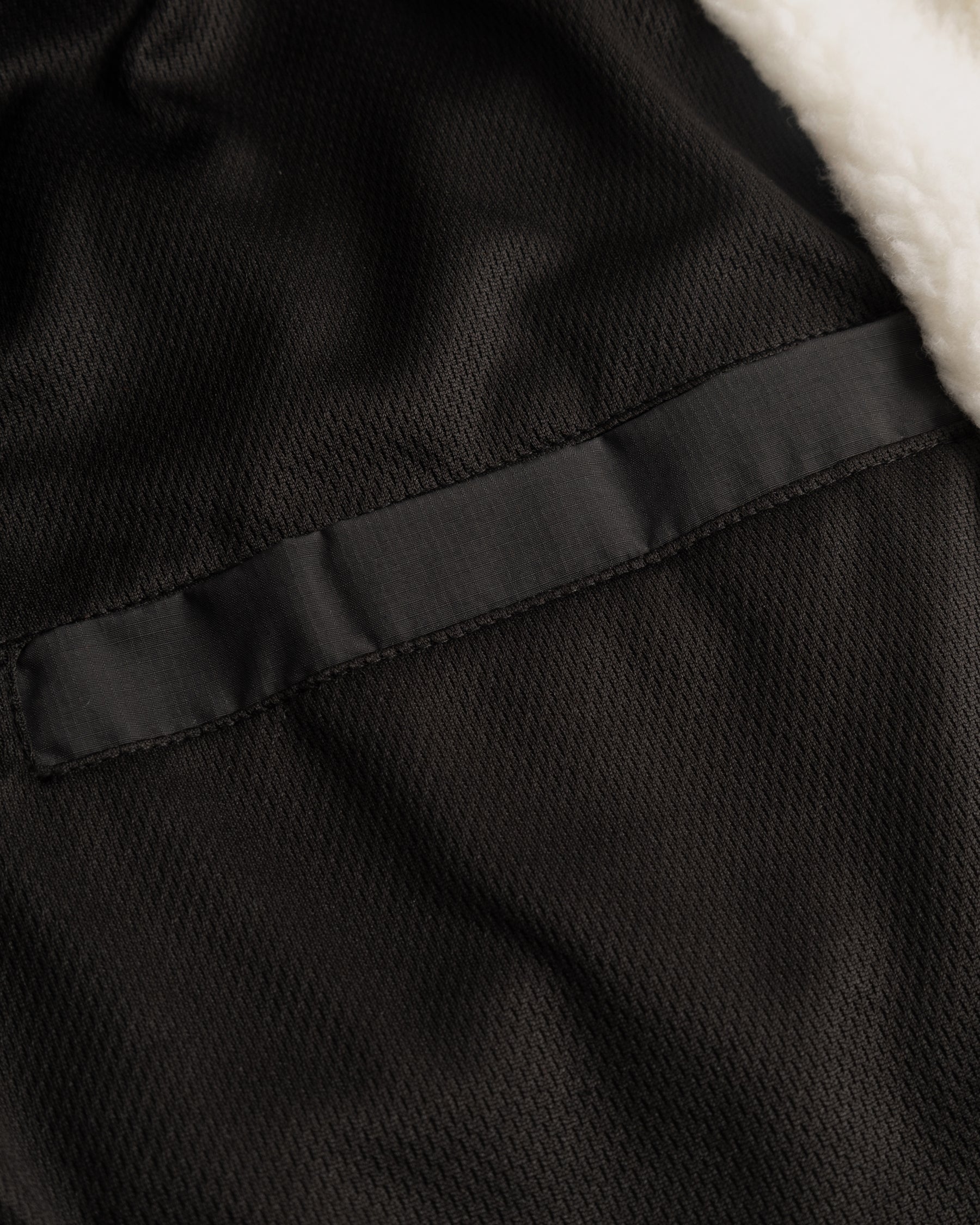 Innenseite der Cropped Teddy Fleecejacke ‚Carey‘ mit schwarzem Textilfutter und weißem Teddyfellrand
