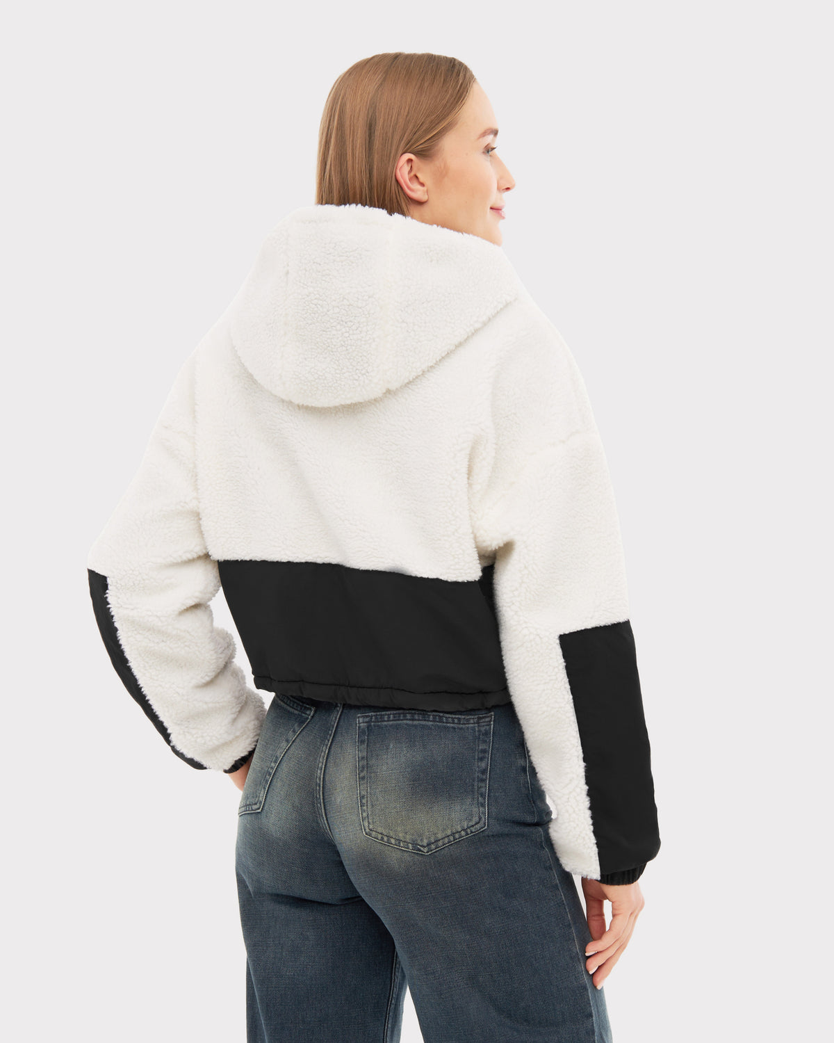Damen trägt Cropped Teddy Fleecejacke 'Carey' in Creme mit schwarzem Einsatz auf Rücken und Ärmeln