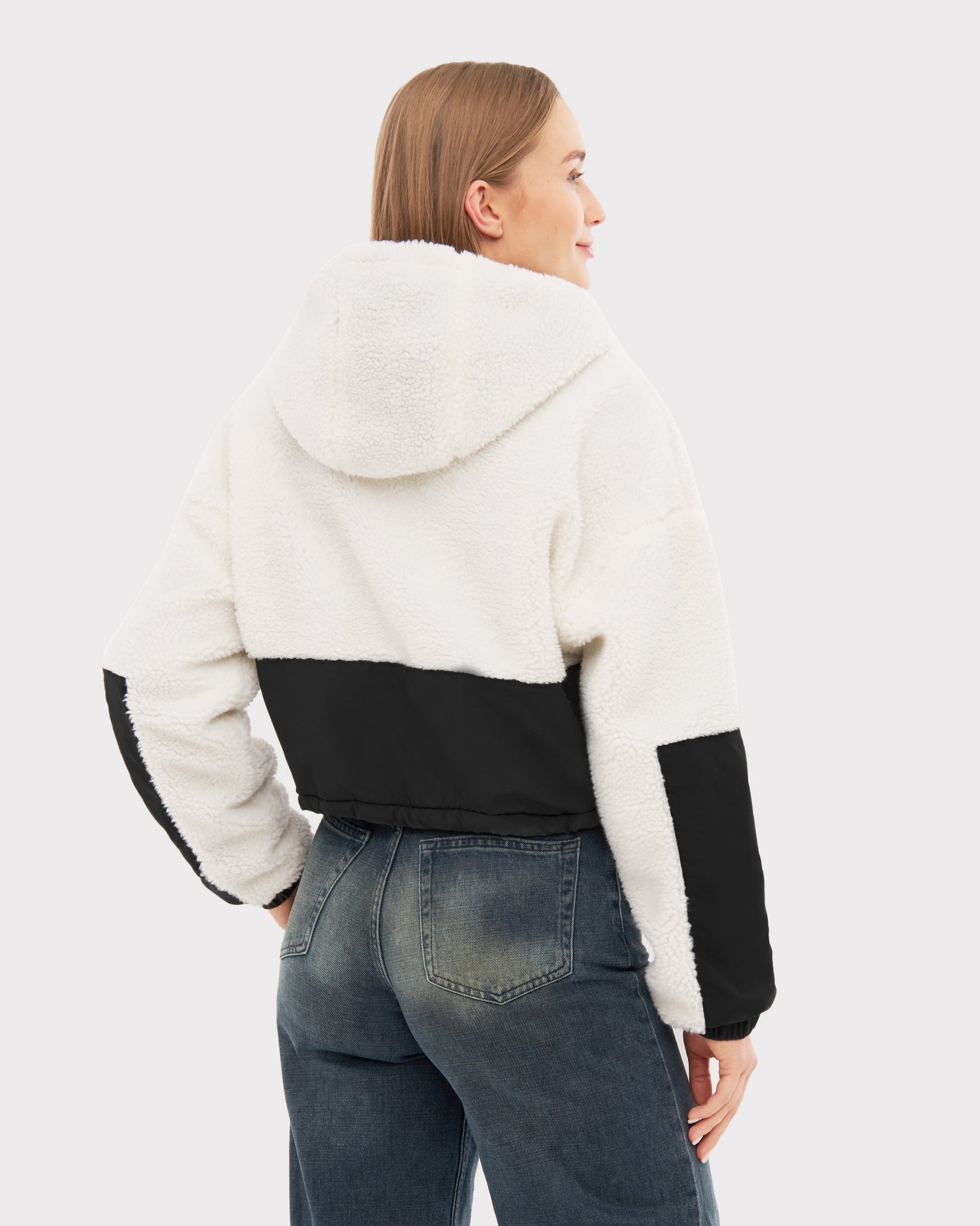 Damen trägt Cropped Teddy Fleecejacke 'Carey' in Creme mit schwarzem Einsatz auf Rücken und Ärmeln