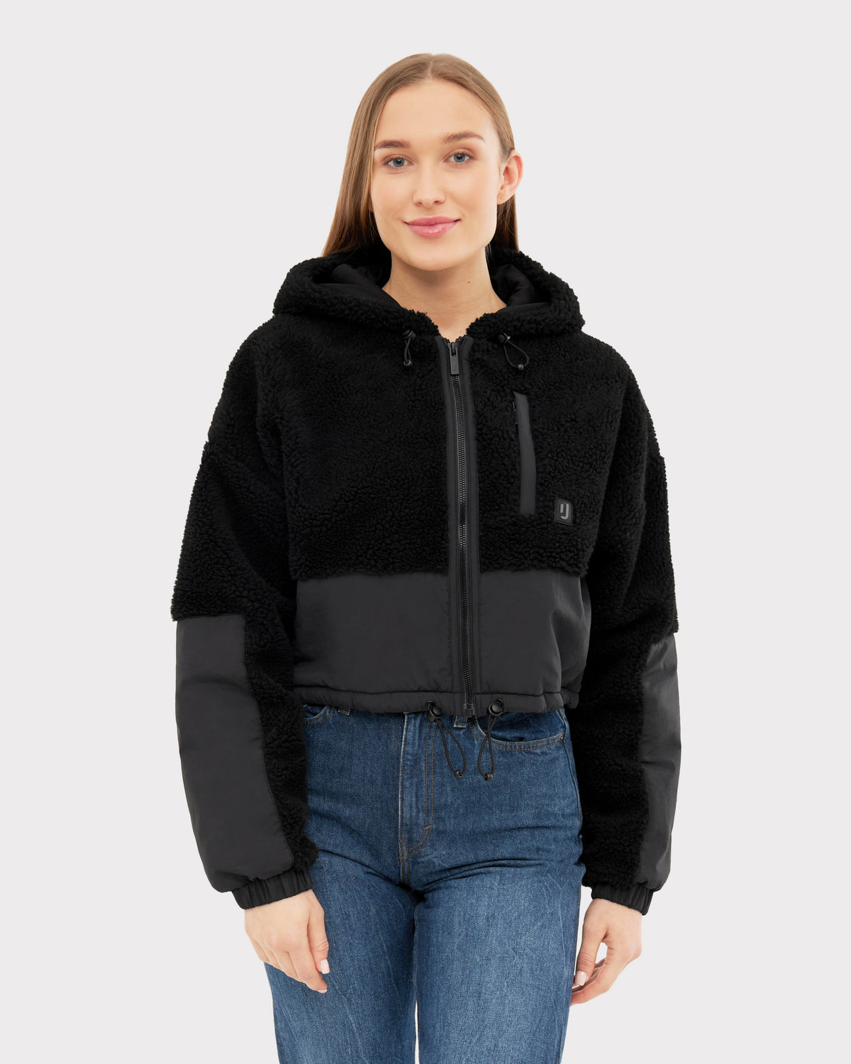 Frau trägt schwarze Cropped Teddy Fleecejacke 'Carey' mit Kapuze und Reißverschluss