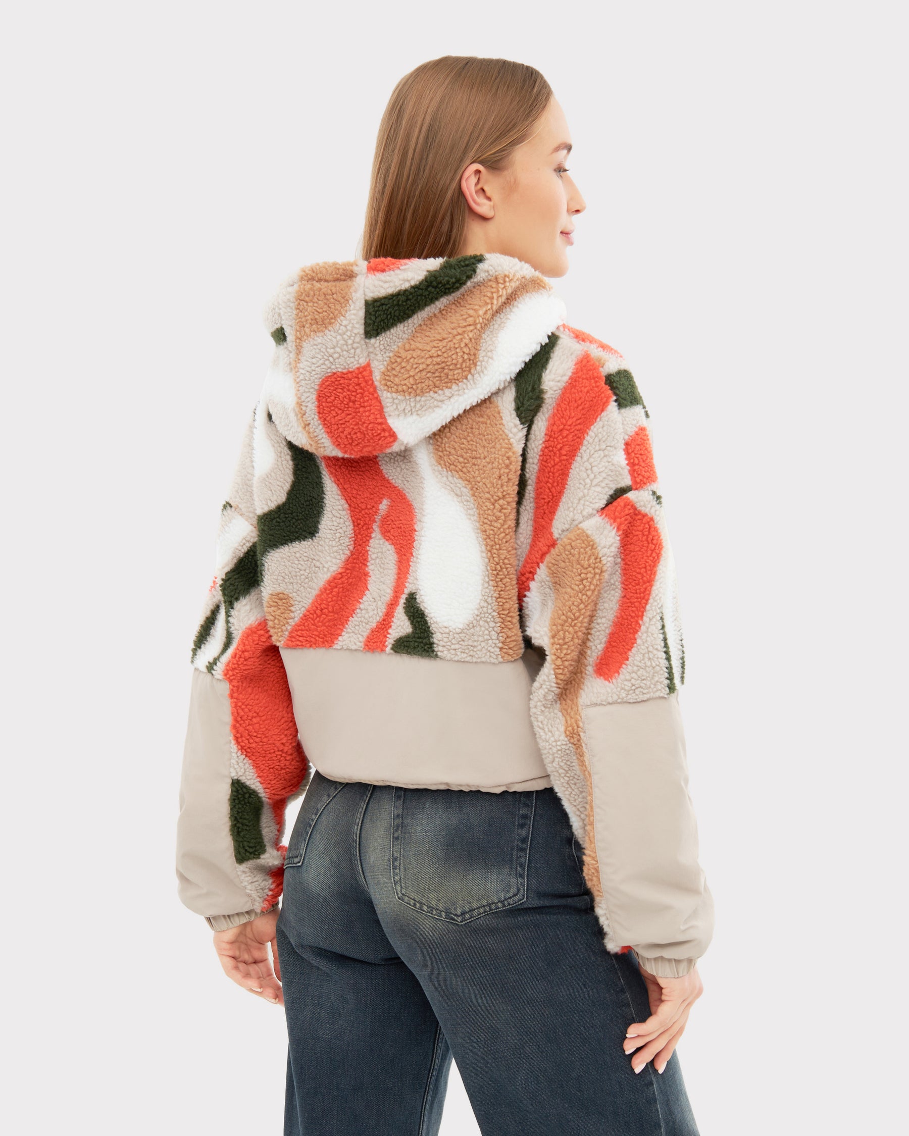 Frau trägt Cropped Teddy Fleecejacke 'Carey' mit Kapuze in buntem abstraktem Muster von hinten