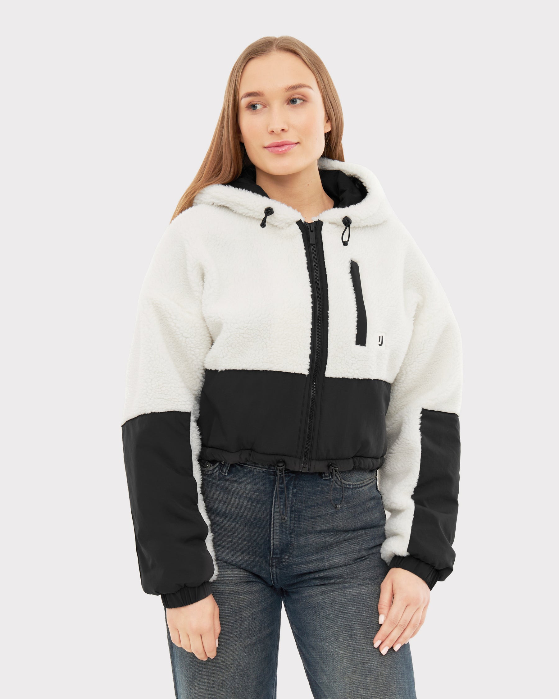 Frau trägt weiße und schwarze Cropped Teddy Fleecejacke 'Carey' mit Kapuze und Reißverschluss