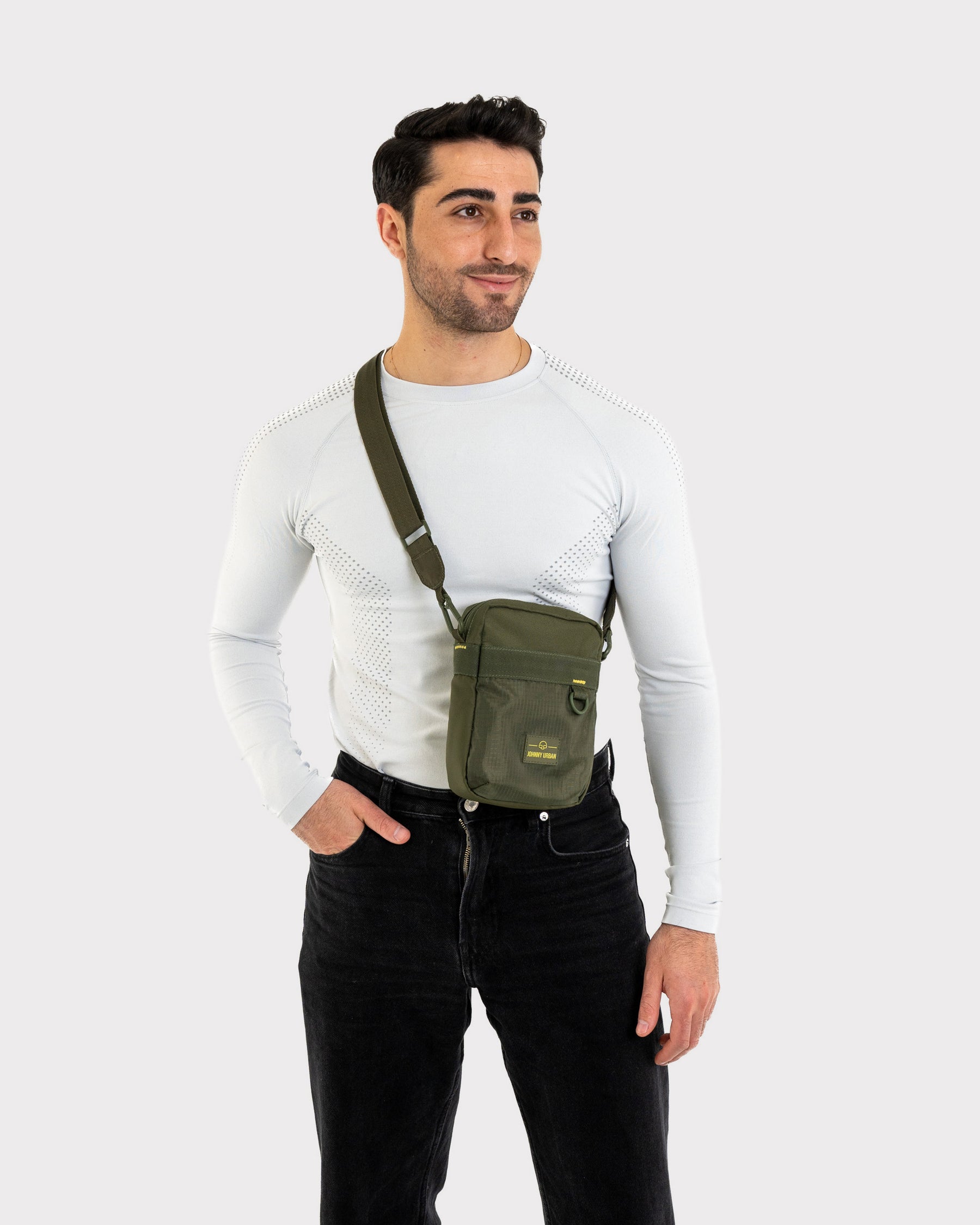 Mann trägt olivgrüne Johnny Urban Umhängetasche 'Jayden' über weißem Langarmshirt und schwarzer Hose