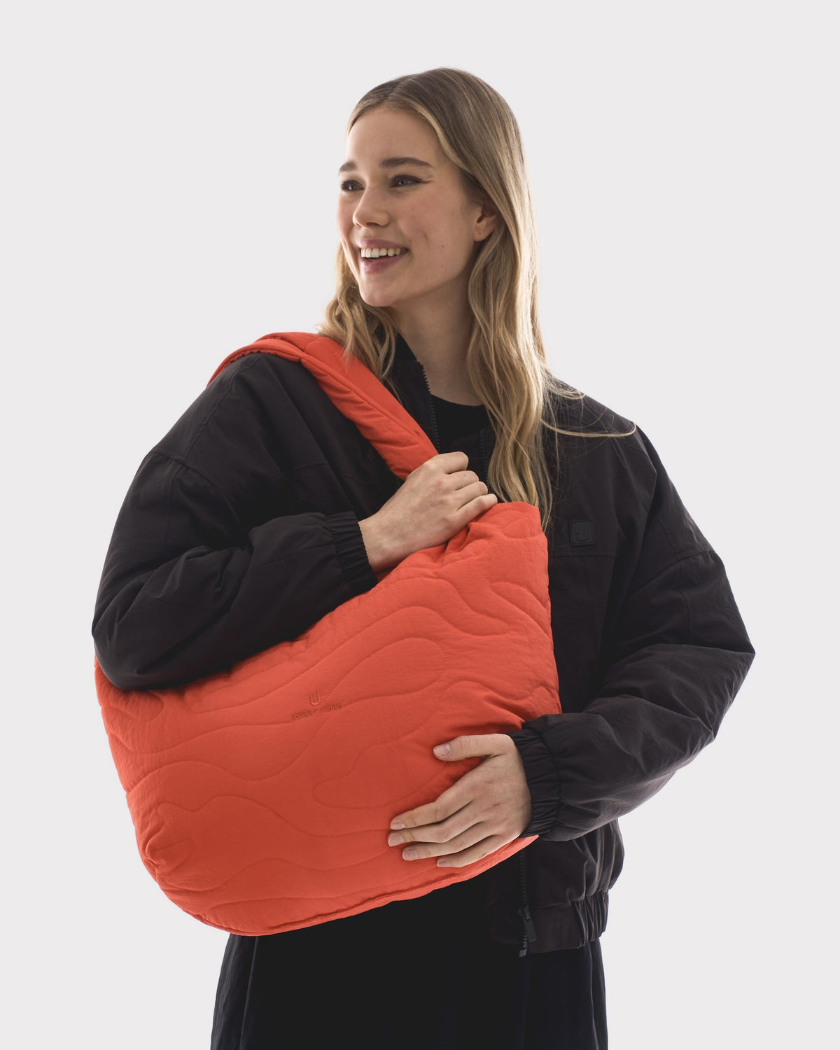Unser weibliches Model präsentiert hier die Shopper-Bag "Cleo" in einzigartigem coral-rot. 