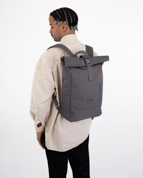 Mann von hinten mit beigem Hemd und grauem Rolltop Rucksack ‚Robin Medium‘