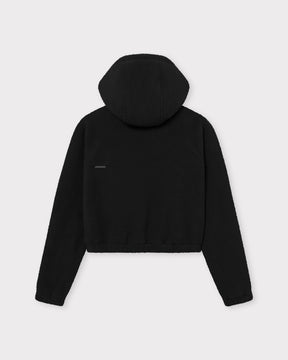 Die Rückseite unserer cropped Fleecejacke Nova bietet dir einen weichen Saum und entspannten Tragekomfort - hier in Schwarz. 