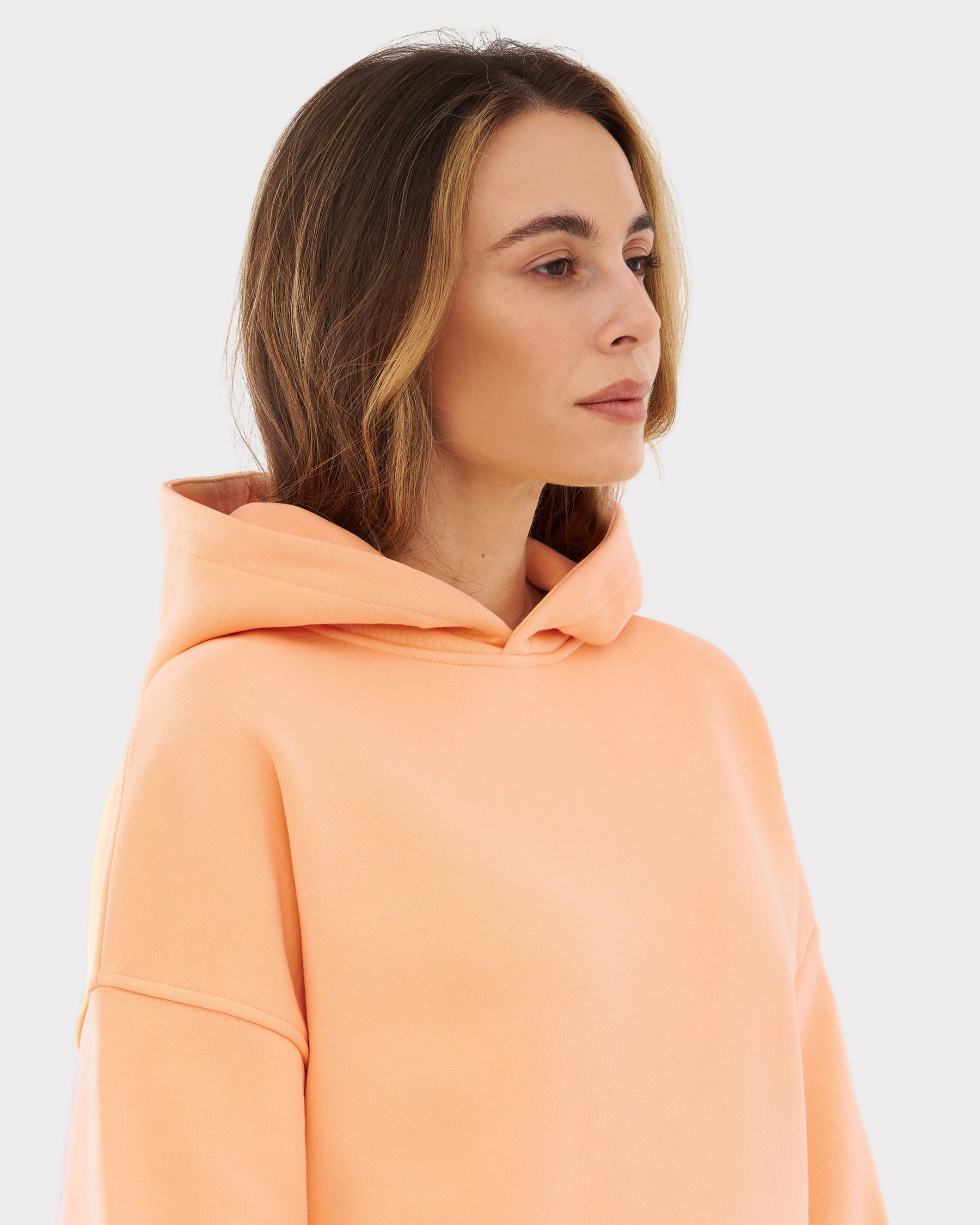 Dame trägt peachfarbigen oversized Hoodie 'Cody' mit Kapuze