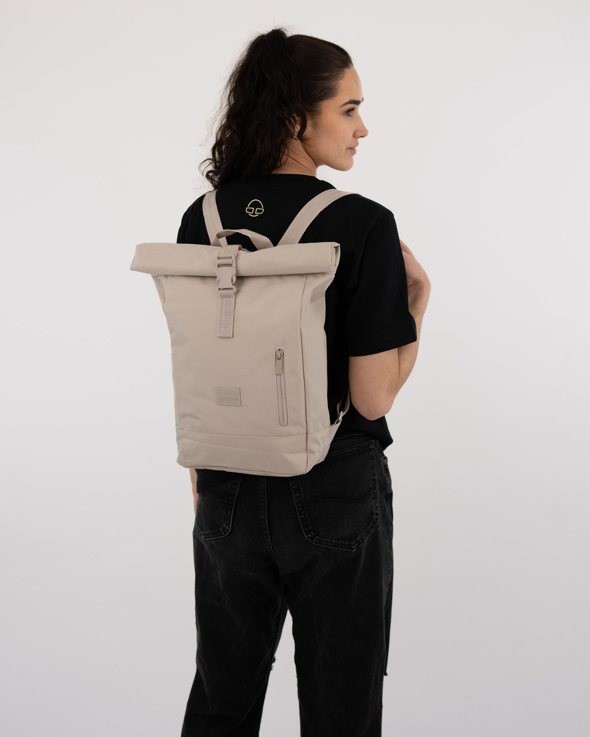 Damen-Rolltop-Rucksack 'Robin Small' in Beige getragen von Frau mit schwarzem T-Shirt und schwarzen Jeans