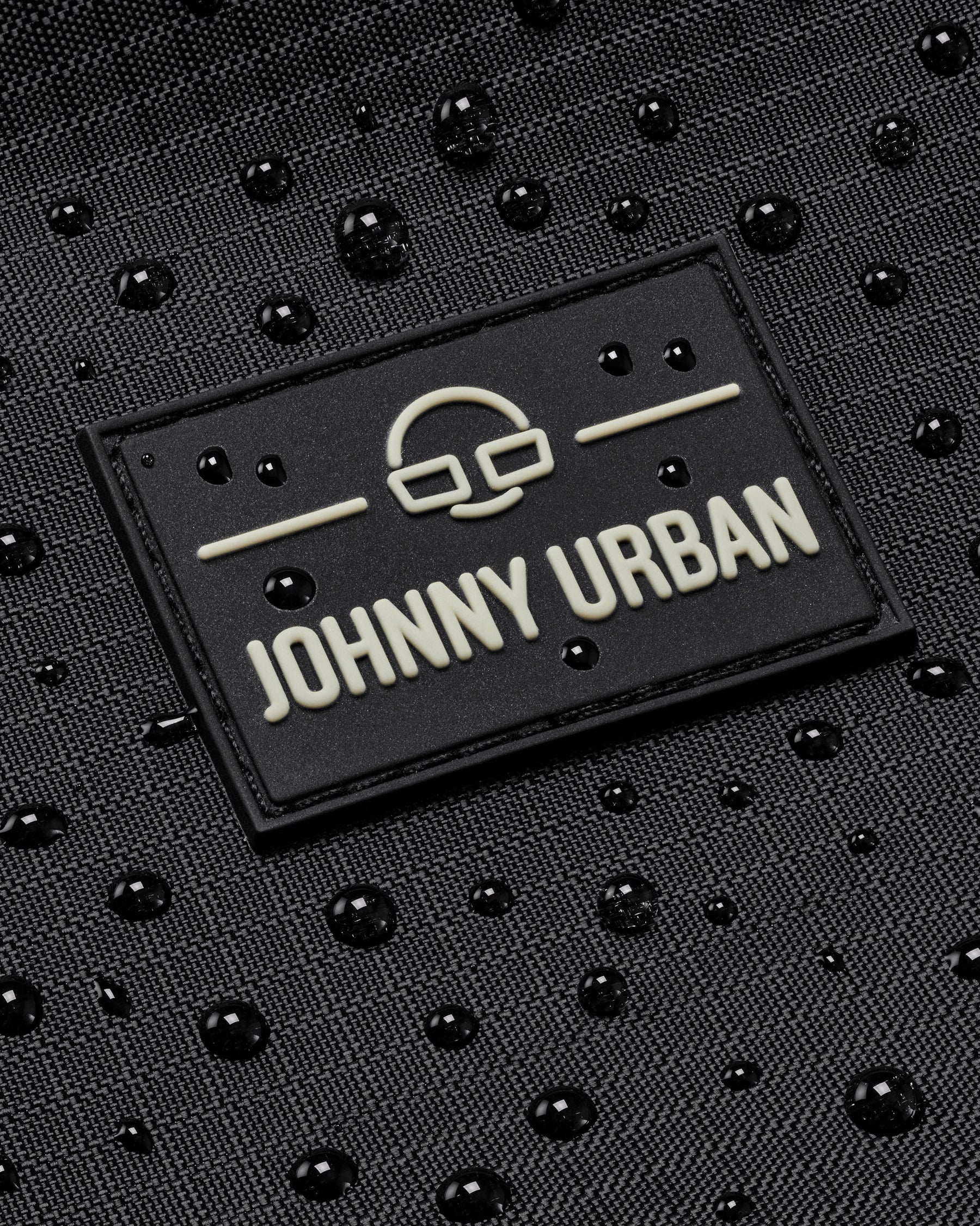 Schwarzes, wasserabweisendes Material mit Johnny Urban Logo und Wassertröpfchen