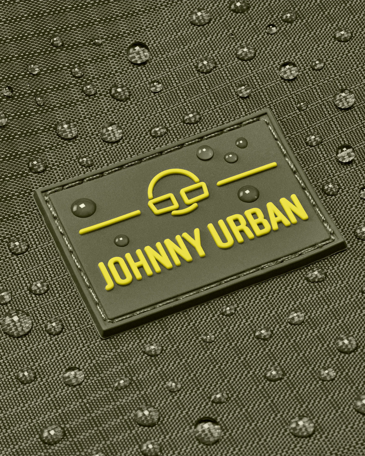 Nahaufnahme des wasserabweisenden Materials einer Johnny Urban Duffle Bag ‚Shawn Large‘ mit Logo und Wassertropfen