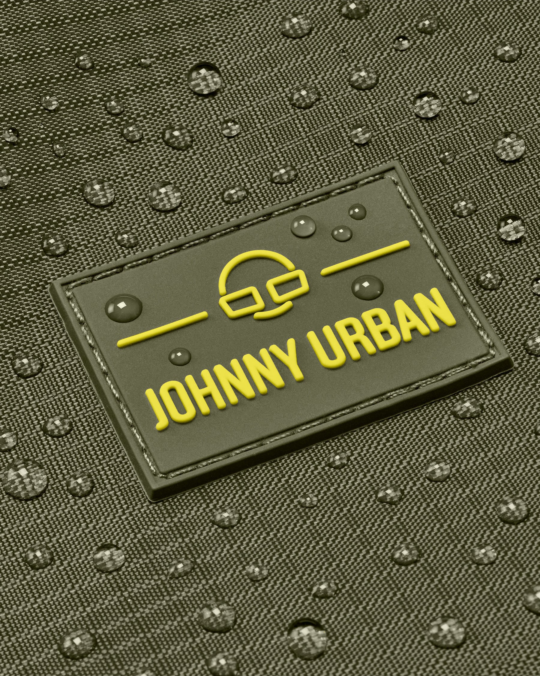 Nahaufnahme des wasserabweisenden Materials einer Johnny Urban Duffle Bag ‚Shawn Large‘ mit Logo und Wassertropfen