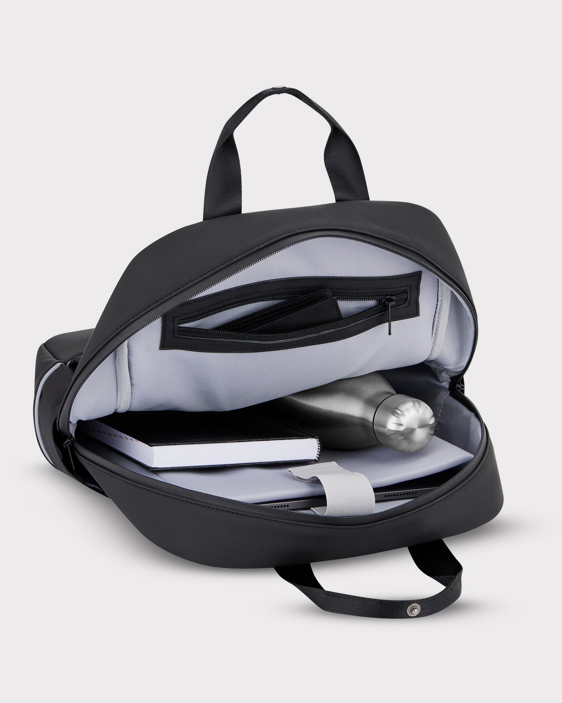 Geöffneter schwarzer Jona Medium Rucksack mit Laptopfach, Notizbuch, Metallflasche und Reißverschlusstasche innen