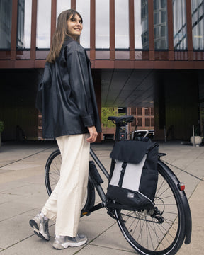 Frau neben Fahrrad mit reflektierendem Rucksack 'Mika' von Johnny Urban am Gepäckträger