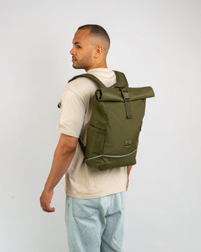 Mann trägt olivgrünen Rolltop Rucksack ‚Robin Medium‘ mit reflektierendem Streifen