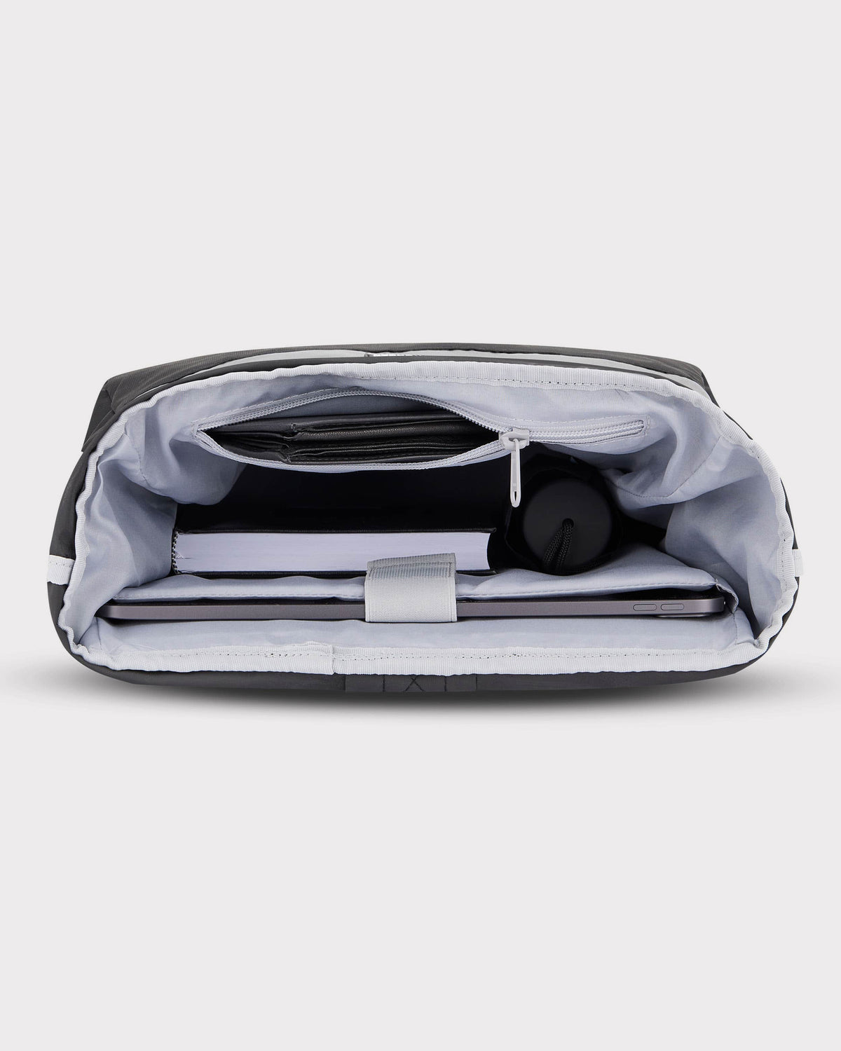 Innenansicht des Rolltop Rucksacks 'Robin Medium' mit Laptop, Buch, Flasche und Reißverschlusstasche