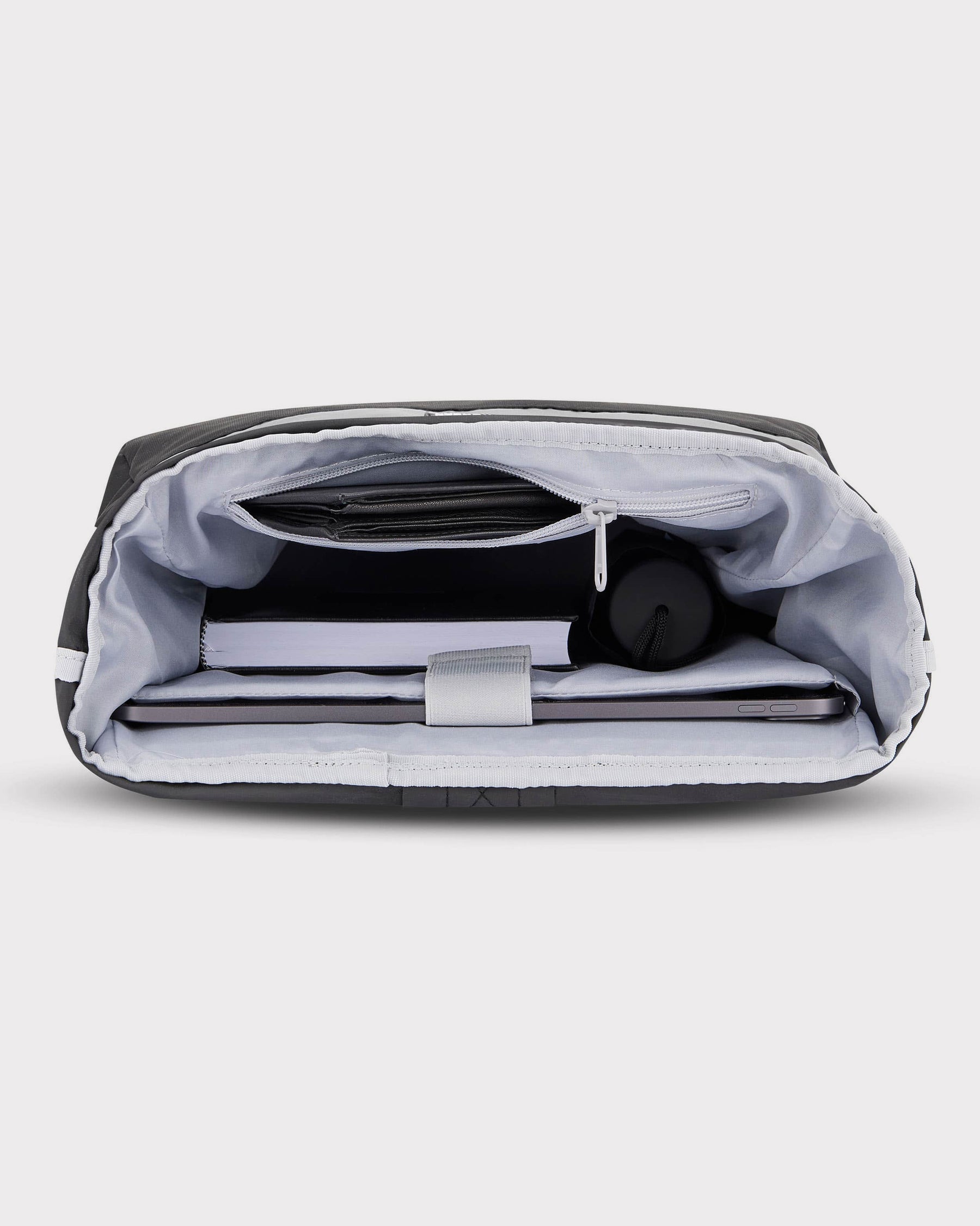 Innenansicht des Rolltop Rucksacks 'Robin Medium' mit Laptop, Buch, Flasche und Reißverschlusstasche