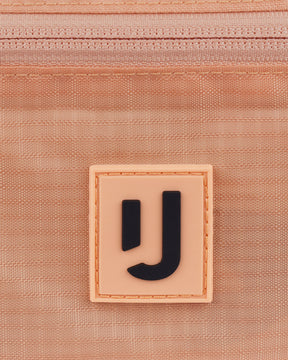 Nahe Aufnahme des Johnny Urban Logos auf der wasserabweisenden 2in1 Bauchtasche 'Jimmy' in Peach-Farbe