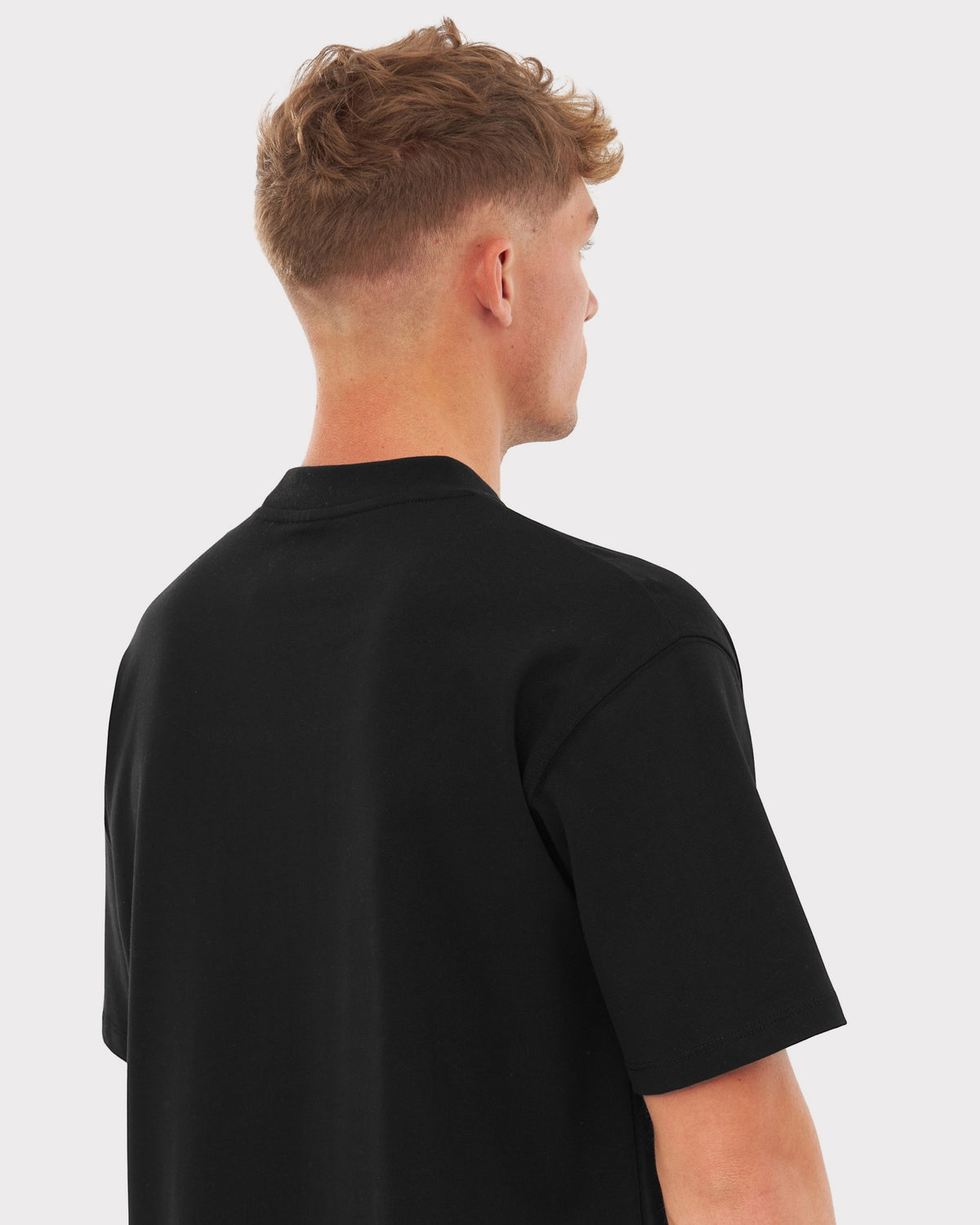 Mann trägt schwarzes T-Shirt 'Sammy Johnny Urban', Rückansicht, kurze Ärmel, lockere Passform