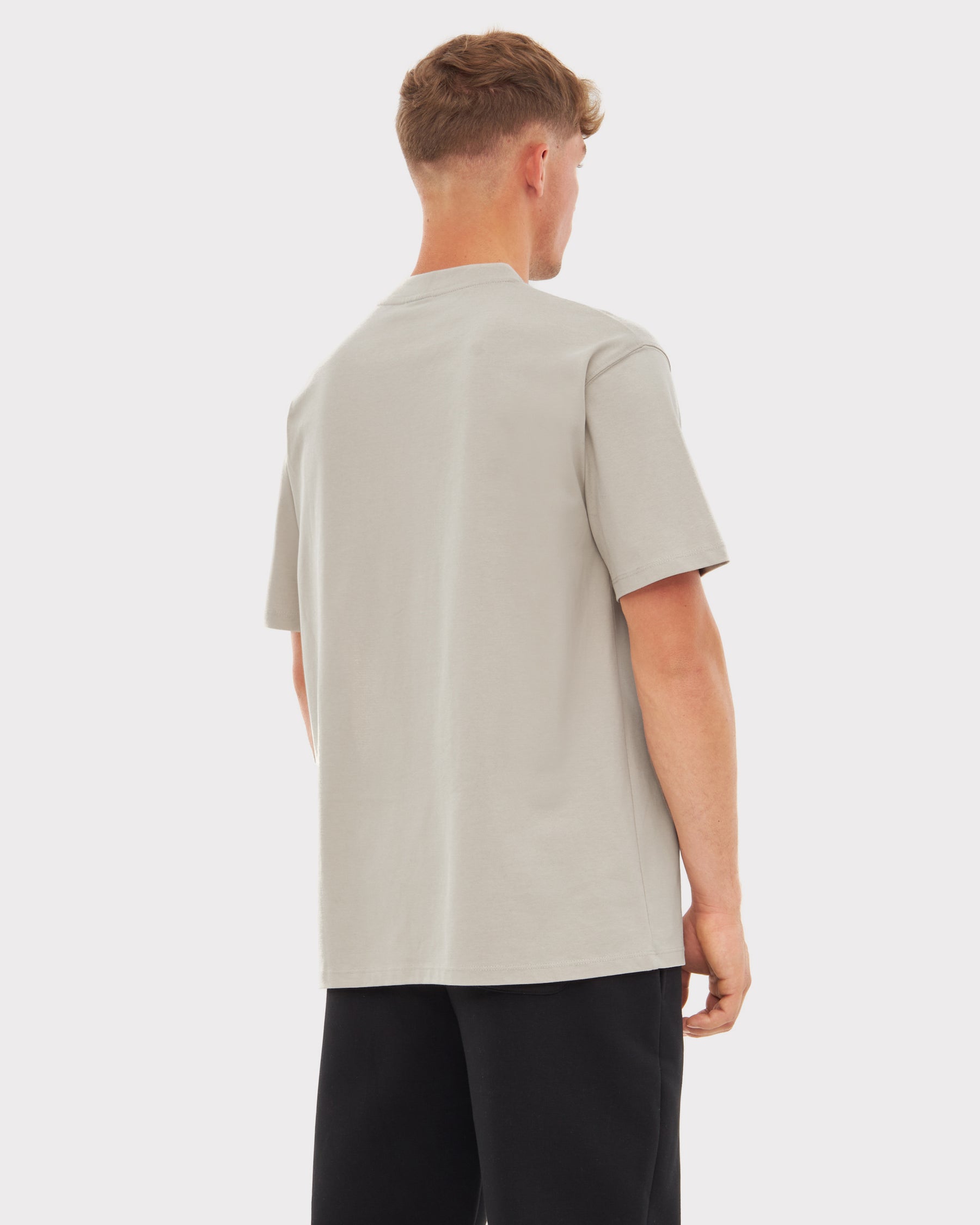 Rückansicht eines Mannes mit sandfarbenem T-Shirt 'Sammy Johnny Urban' und schwarzen Hosen