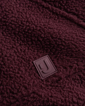Unsere hochwertiges Logo-Badge auf der Fleecejacke Nova in Burgunderrot.  