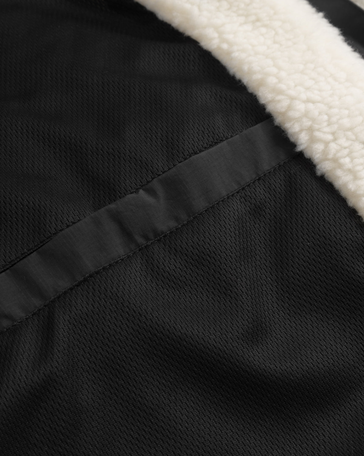 Nahaufnahme eines schwarzen Taschenverschlusses und cremefarbener Teddyfleece-Innenseite der Teddy Fleecejacke 'Carson'