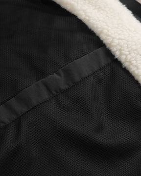 Nahaufnahme eines schwarzen Taschenverschlusses und cremefarbener Teddyfleece-Innenseite der Teddy Fleecejacke 'Carson'