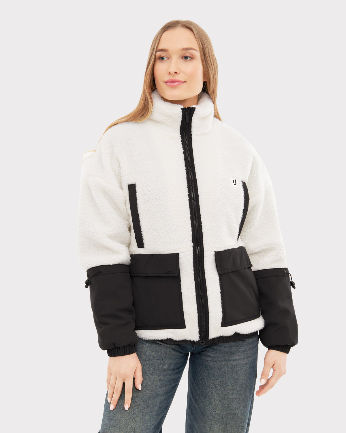 Frau trägt Teddy Fleecejacke 'Carson' in Creme mit schwarzen Details und Reißverschluss