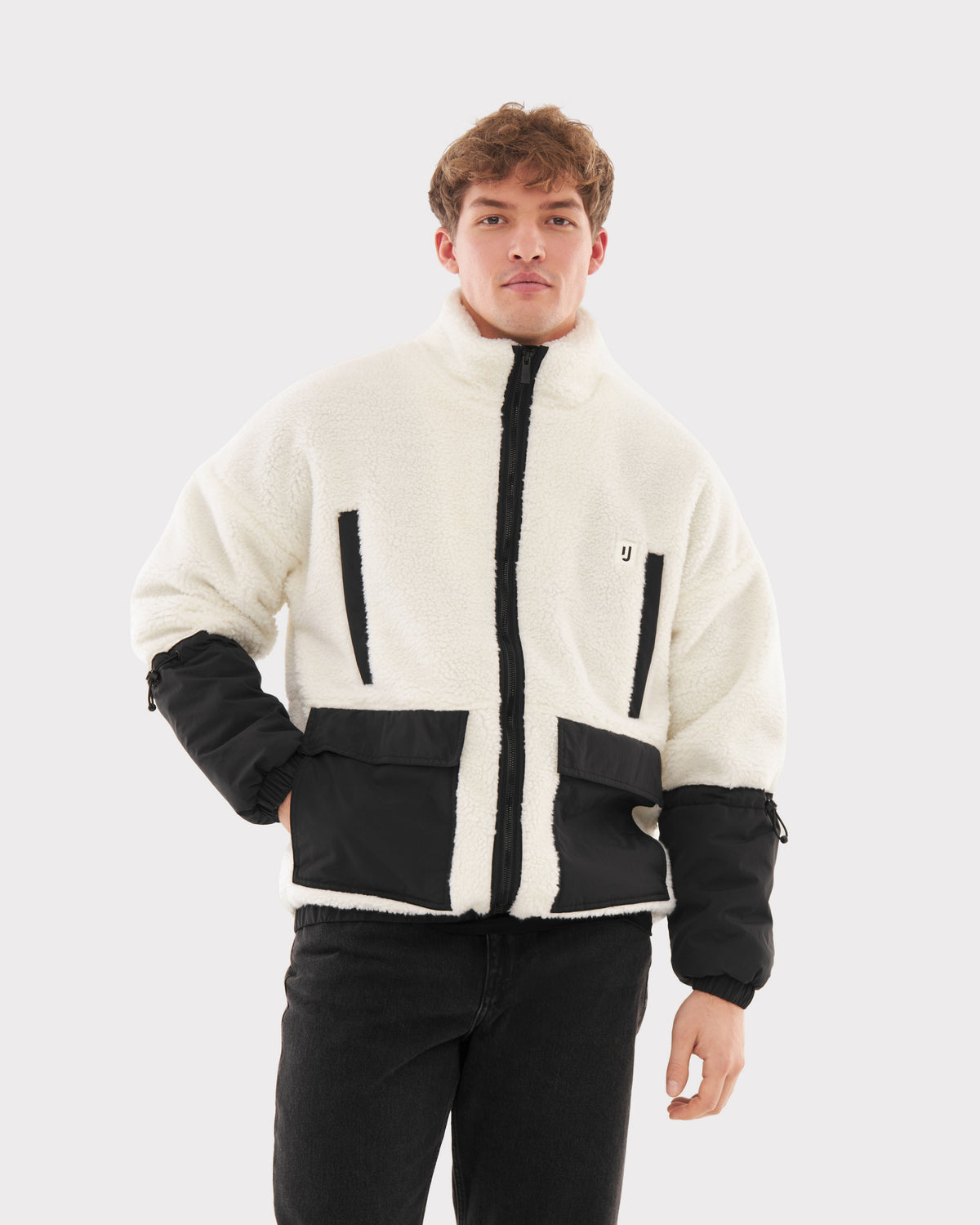Mann trägt Teddy Fleecejacke 'Carson' in Creme mit schwarzen Taschen und Ärmeln