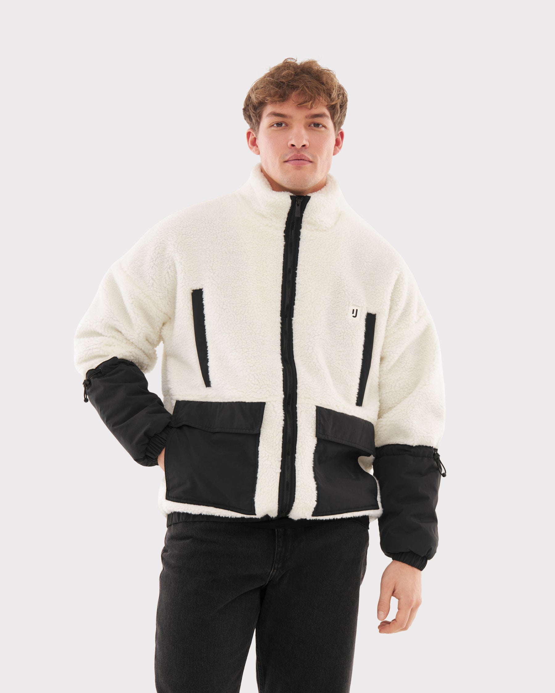 Mann trägt Teddy Fleecejacke 'Carson' in Creme mit schwarzen Taschen und Ärmeln