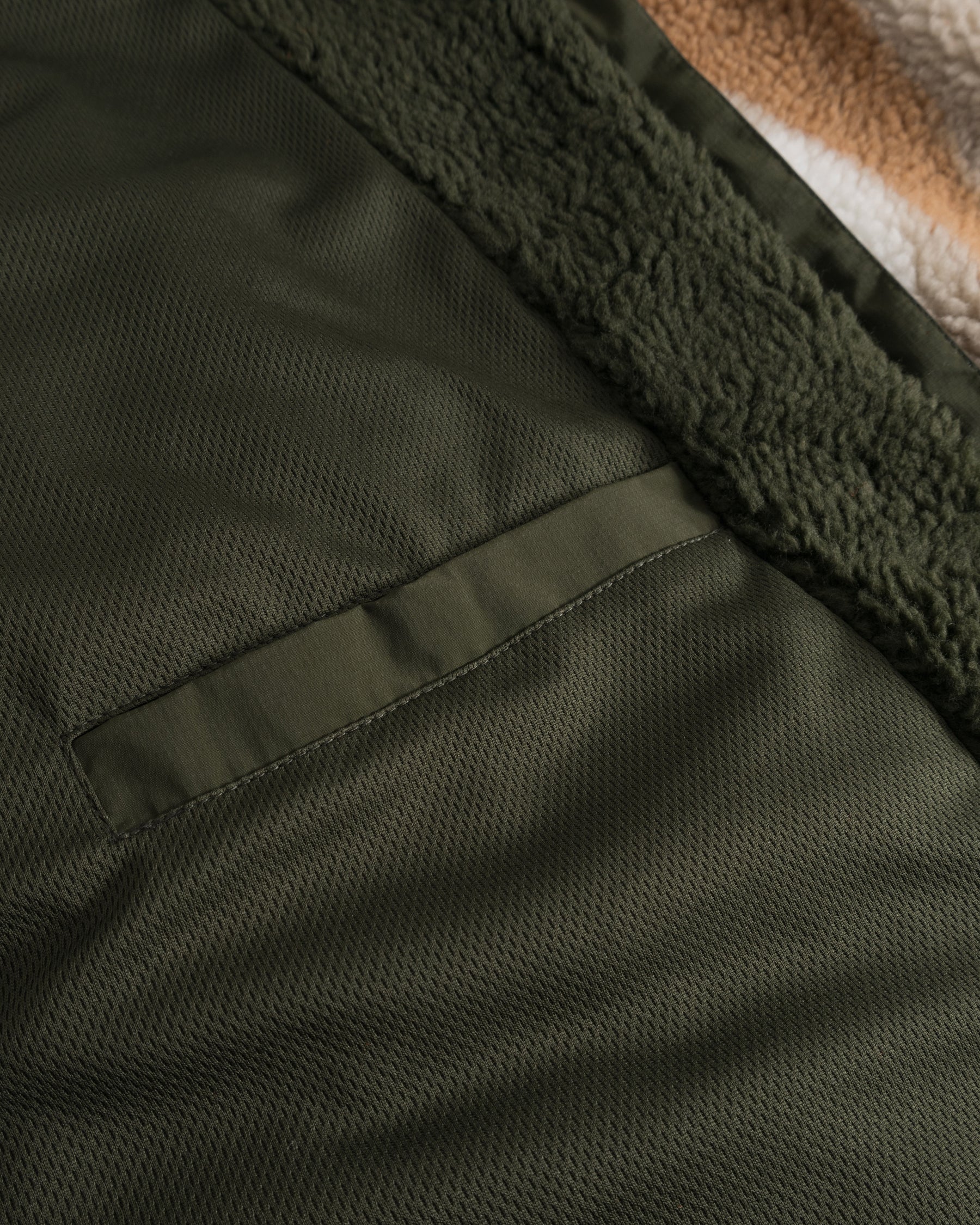 Detailaufnahme der dunkelolivgrünen Innen- und Fleeceaußenseite der Teddy Fleecejacke 'Carson'