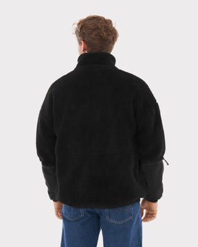 Mann trägt schwarze Teddy Fleecejacke 'Carson' von hinten, kombiniert mit blauen Jeans
