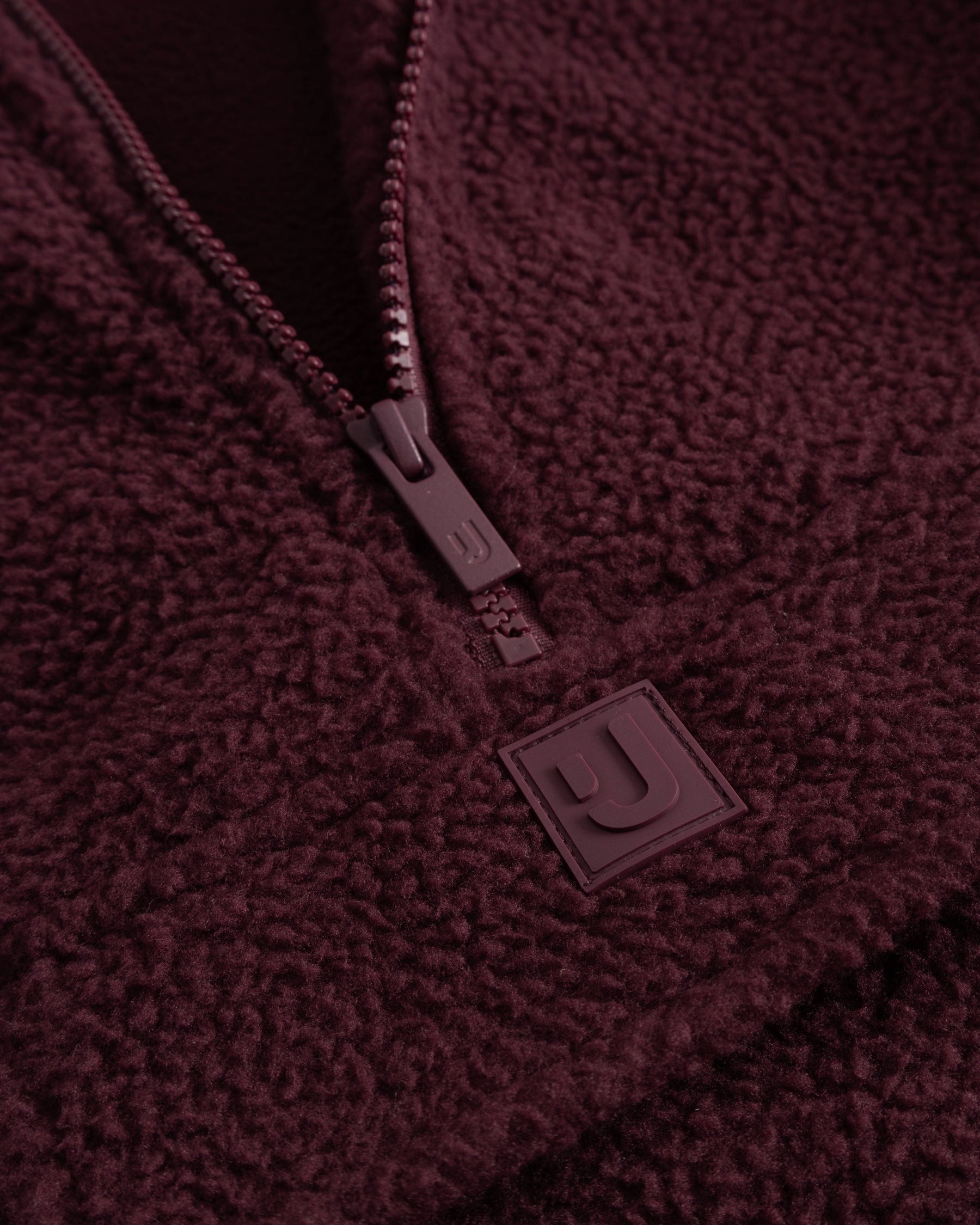Unser hochwertiges Logo-Badge auf dem Fleecepullover Ruben in Burgunderrot. 