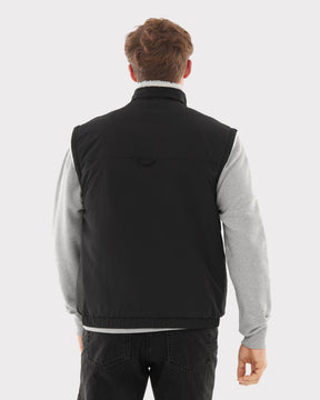 Rückansicht eines Mannes mit schwarzer Fleeceweste über grauem Pullover und schwarzen Jeans
