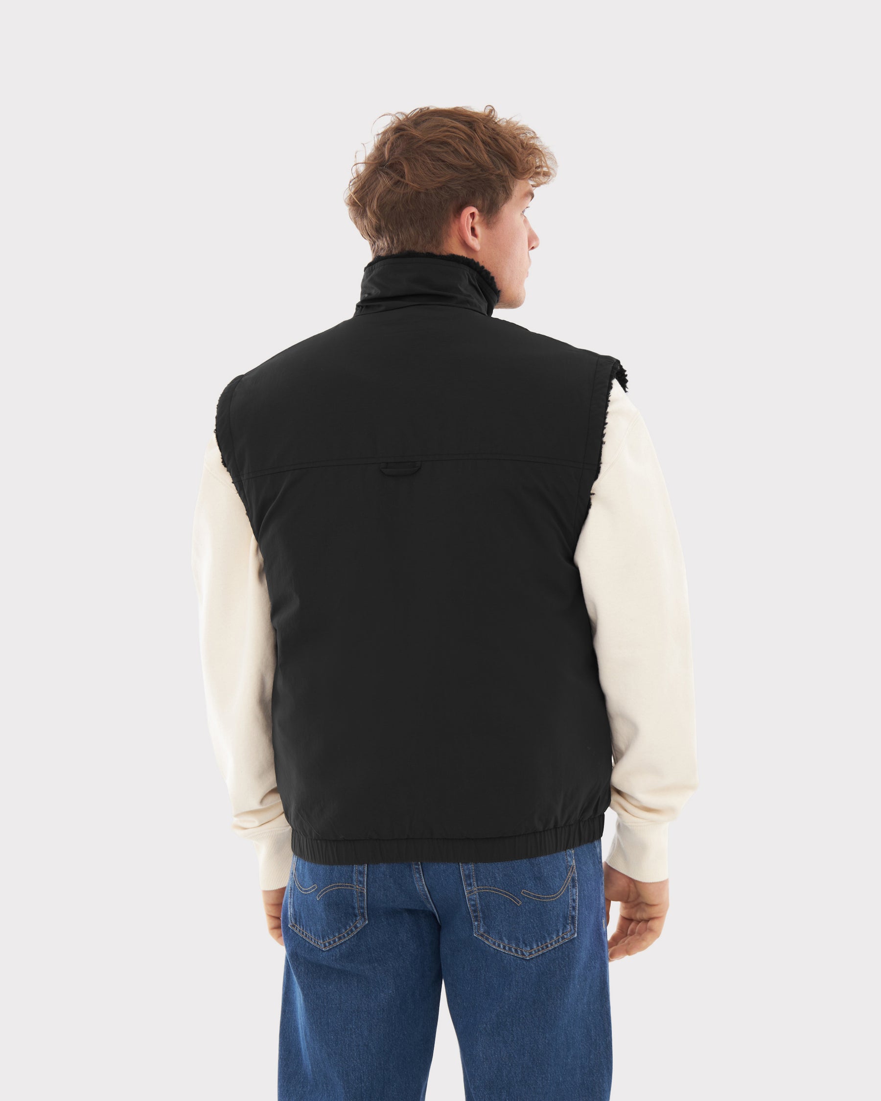 Männliches Modell trägt schwarze Teddy Fleeceweste 'Bryson', weiße Langarmshirt und blaue Jeans, Rückansicht
