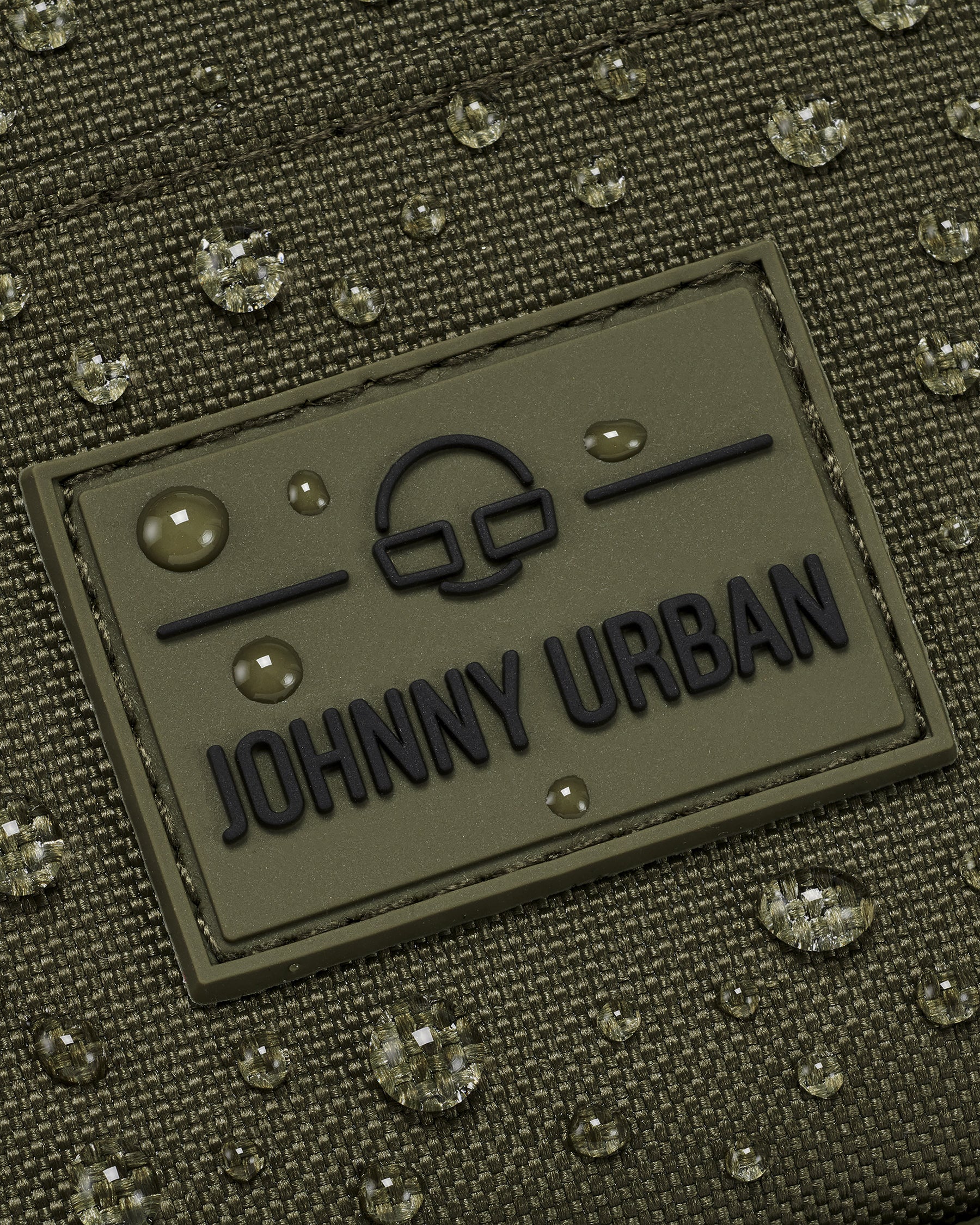 Wasserabweisender Front Pack 'Arthur' von Johnny Urban mit aufgenähtem Logo und Wassertropfen auf grünem Stoff