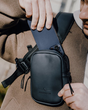 Person steckt ein Smartphone in das schwarze Front Pack 'Toby' von Johnny Urban