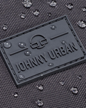 Nahe Aufnahme des wasserdichten, dunkelgrauen Materials der Bauchtasche 'Erik Large' von Johnny Urban mit Logo und Wassertropfen