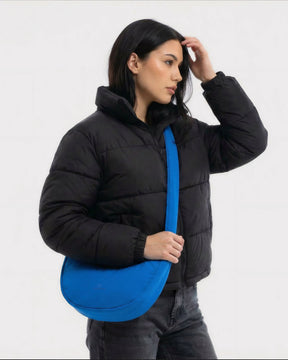 Weibliches Model zeigt sich hier mit der Johnny Urban Half-Moon-Bag "Lou Medium" in blau. | KI generiertes Bild