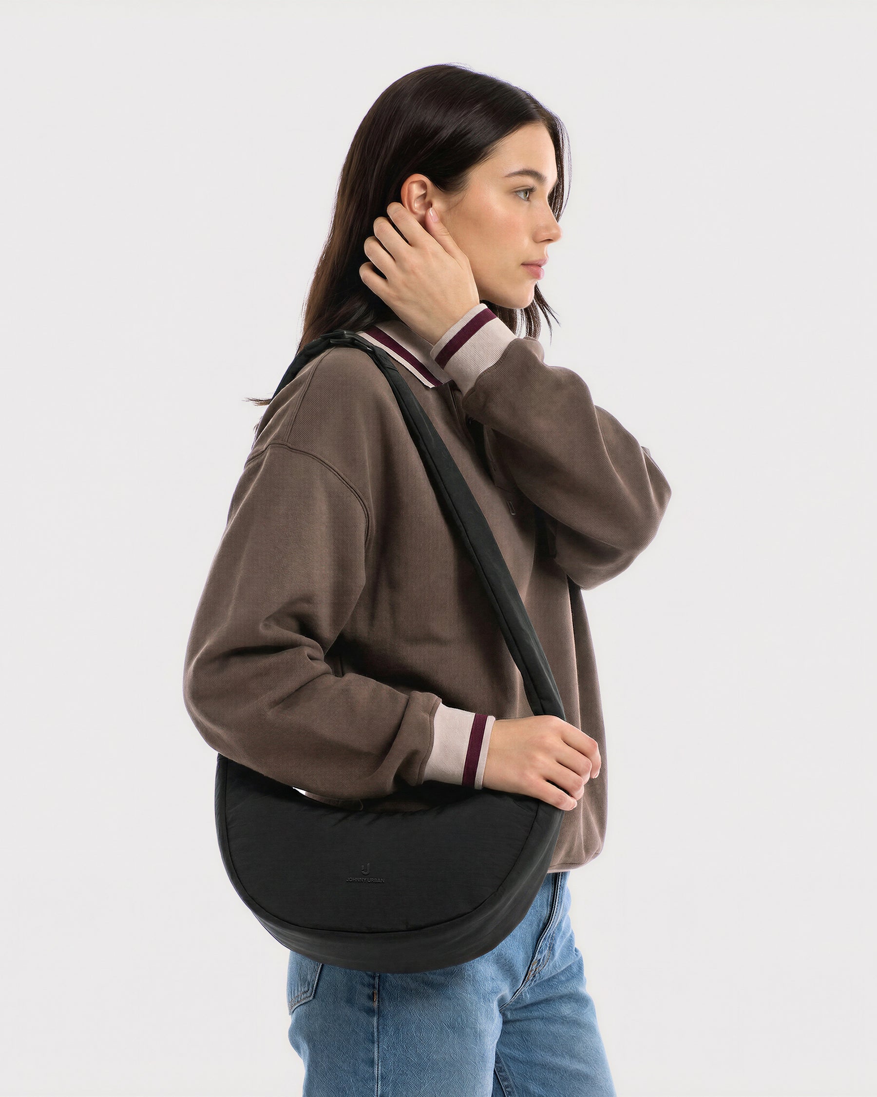 Unser weibliches Model zeigt sich hier mit der Johnny Urban Half-Moon-Bag "Lou Medium" in schwarz. | KI generiertes Bild
