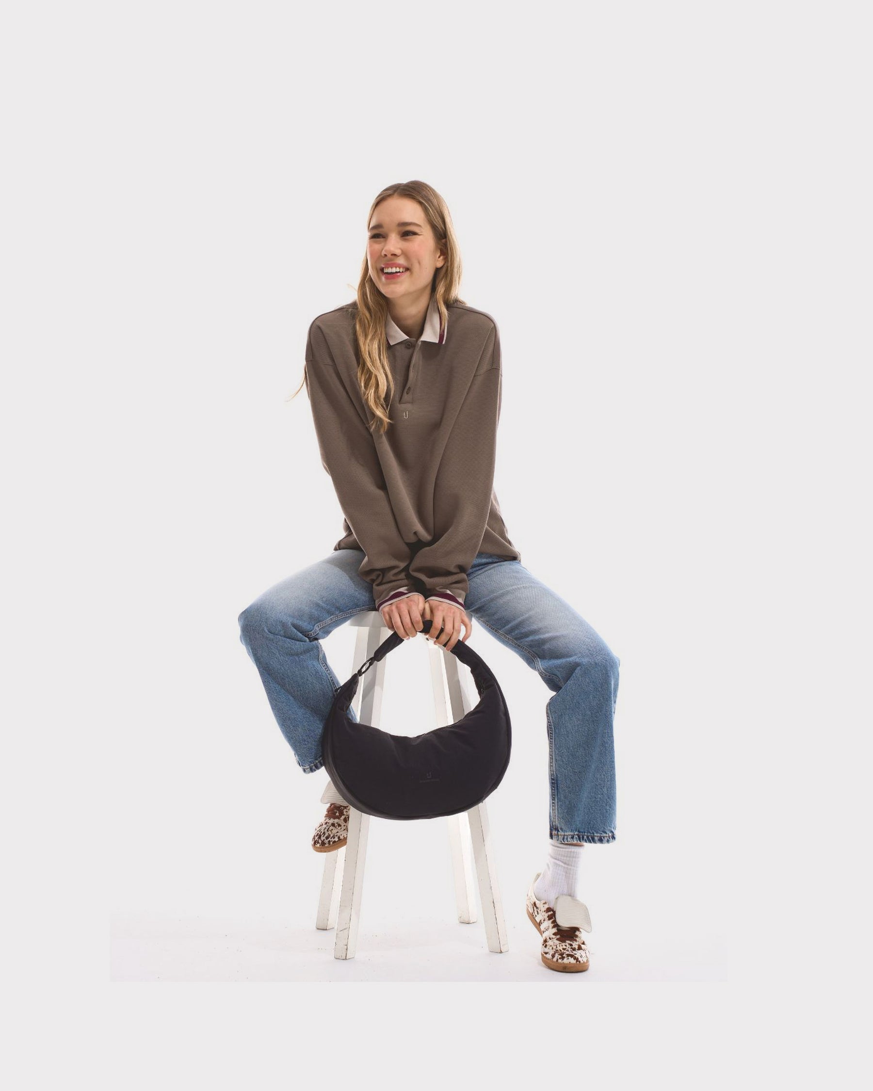 Unser weibliches Model präsentiert sich hier mit der Half-Moon-Bag "Lou Large" in schwarz. 