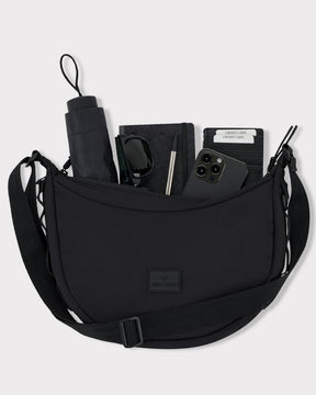Halbmondtasche 'Kaia Medium' in Schwarz mit Regenschirm, Sonnenbrille, Notizbuch, Stift, Smartphone und Kartenetui