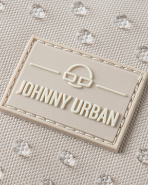 Nahaufnahme des Johnny Urban Logos auf sandfarbenem, wasserabweisendem Stoff mit kleiner Punktstruktur