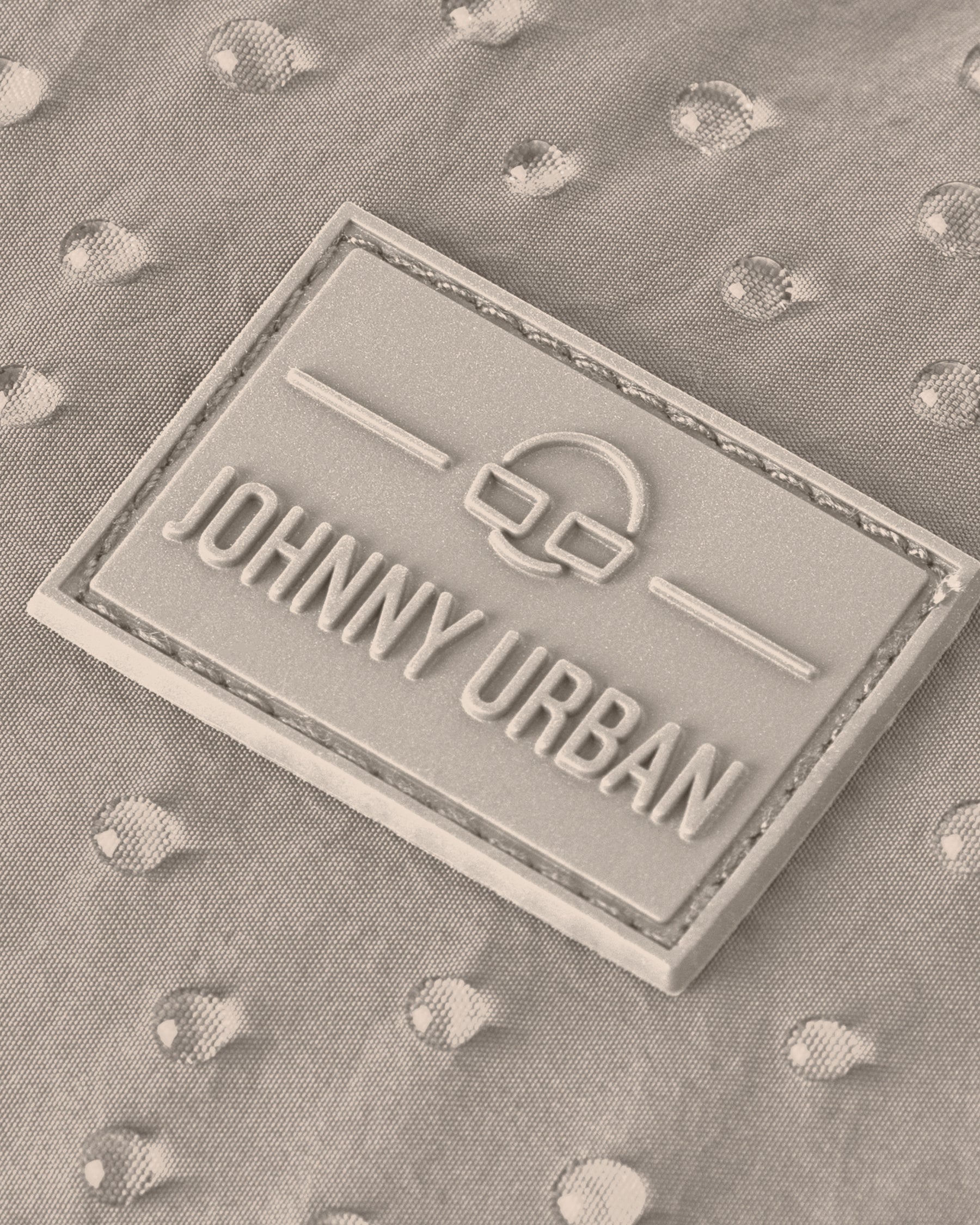 Johnny Urban Markenlabel auf wasserabweisendem beige Stoff mit Wassertropfen