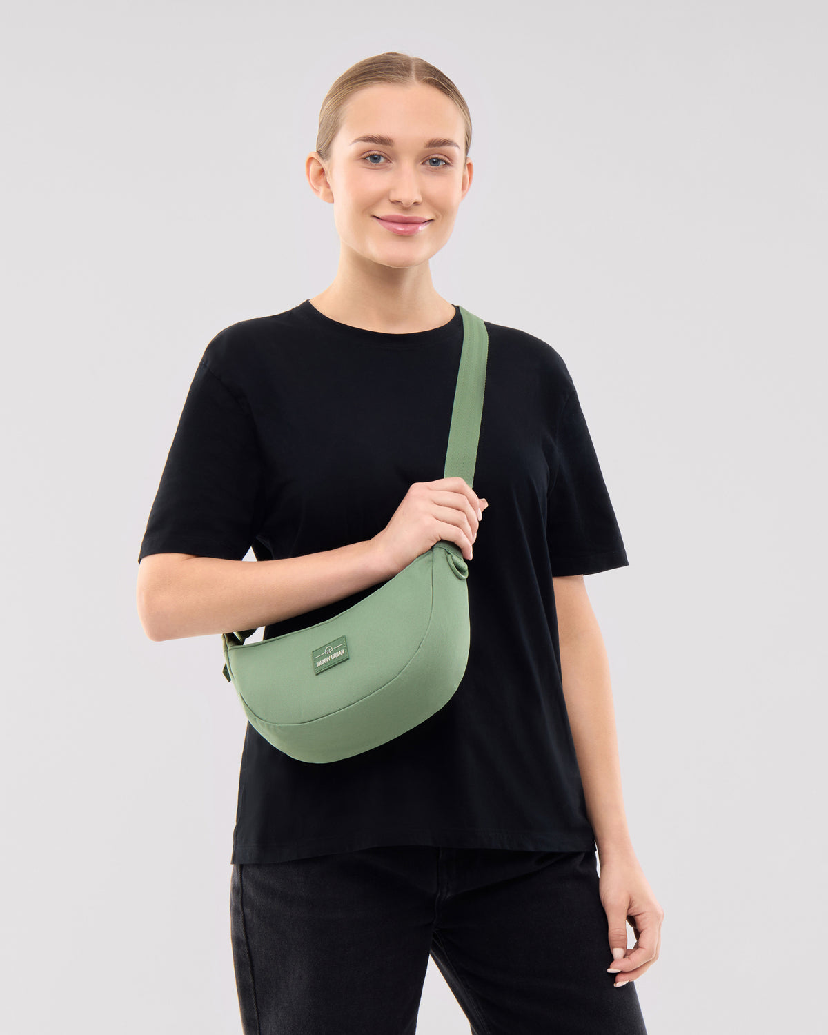 Frau trägt die sage-grüne Half Moon Bag 'Ally Small' von Johnny Urban quer am Körper