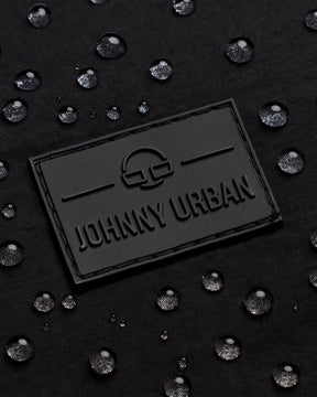 Schwarzes geprägtes Johnny Urban Logo auf wasserabweisendem Material mit Wassertropfen