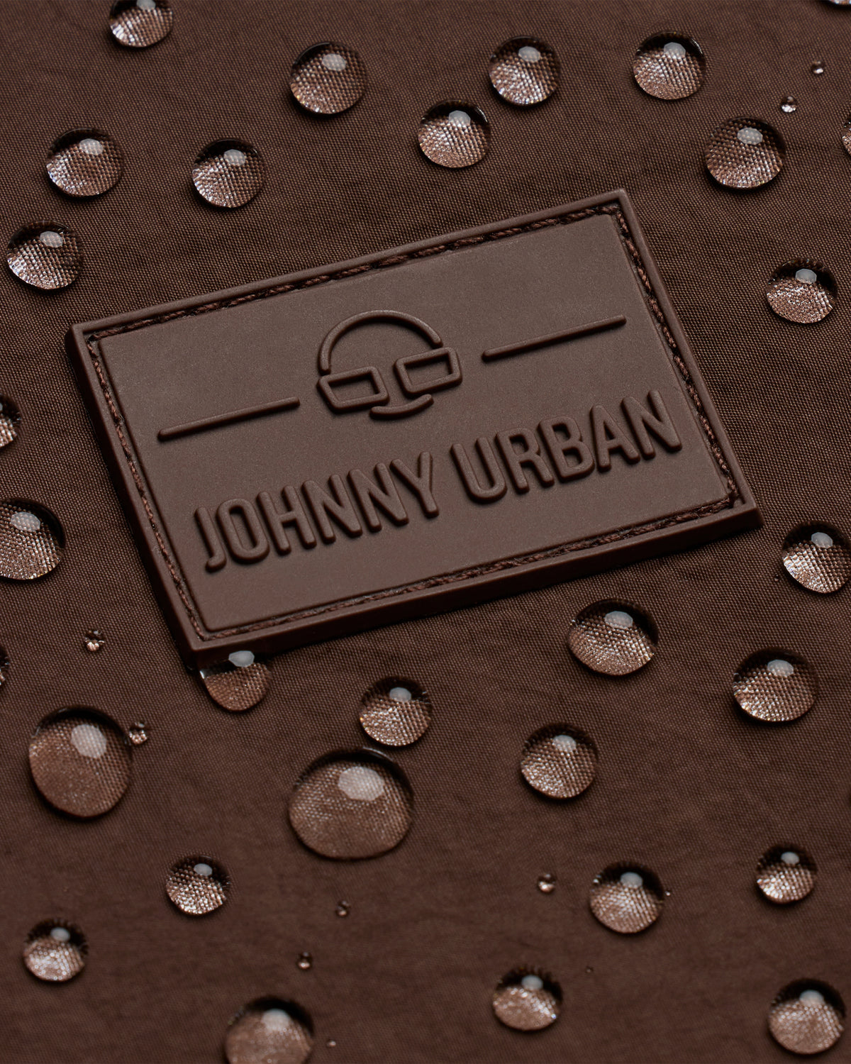 Johhny Urban Logo auf braunem, wasserabweisendem Stoff mit Wassertropfen
