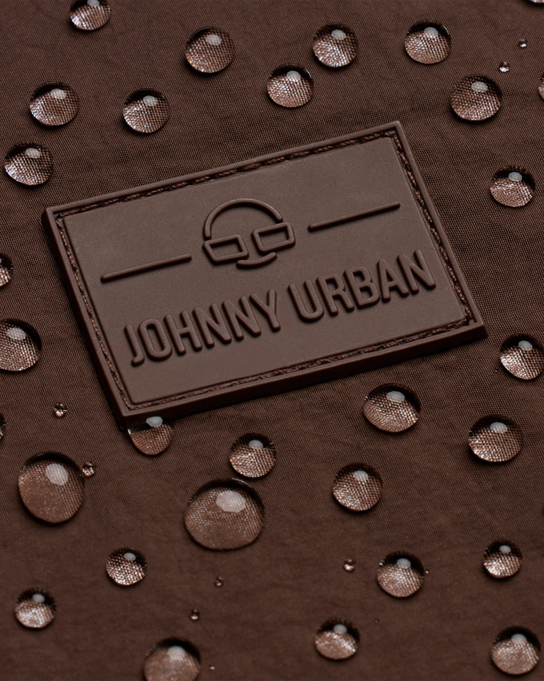 Johhny Urban Logo auf braunem, wasserabweisendem Stoff mit Wassertropfen