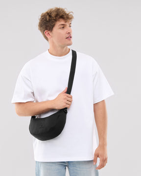 Mann trägt Johnny Urban Half Moon Bag 'Ally Small' in Schwarz quer über den Oberkörper