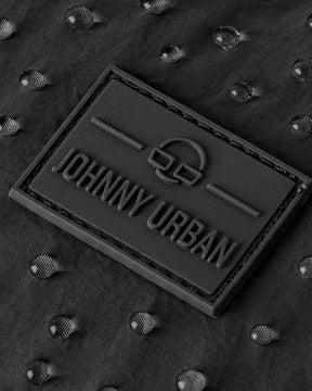 Nahaufnahme des Johnny Urban Logos auf wasserabweisendem, schwarzem Stoff mit Wassertröpfchen